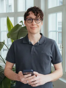 Florian Schiemer im Büro, das Smartphone in der Hand.